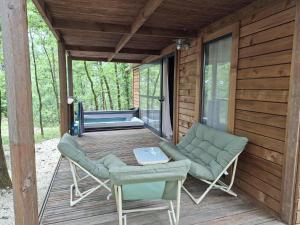 una veranda schermata con 2 sedie e un tavolo di Chalet au bois tranquille a Saint-André-de-Double