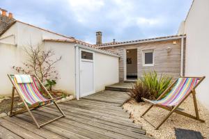 due sedie sedute su una terrazza di legno di fronte a una casa di Agréable Maison Sablaise a Les Sables-dʼOlonne