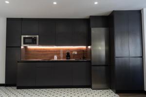 a kitchen with black cabinets and a microwave at La Carrera 7 - Baños Árabes - Parking sujeto a disponibilidad in Jaén
