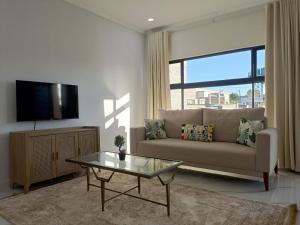un soggiorno con un divano e un tavolo di vetro di Longhorn Ibex Apartments a Lusaka