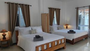 two beds in a room with two large windows at Tropical Sea Front House in Ko Po