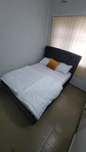una cama grande con sábanas blancas y almohadas amarillas en Hometune, en Lagos