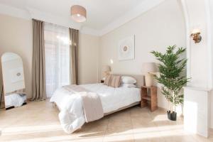 a white bedroom with a bed and a potted plant at MainAvenue White Tower in Thessaloniki