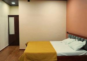 a bedroom with a bed with a yellow blanket on it at Evergreen bliss farm in Karjat
