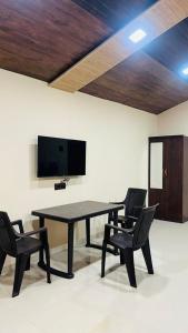 a black table and chairs in a room with a tv at Evergreen bliss farm in Karjat