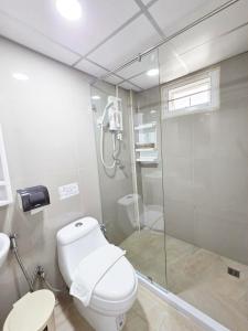 um banheiro com vaso sanitário e box de vidro em PT Grand Hotel em Ban Tha Makham