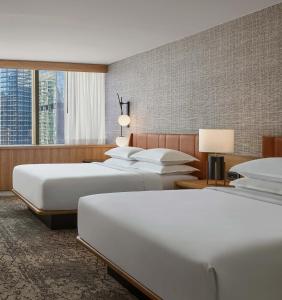 Sheraton Denver Downtown Hotel في دنفر: غرفة فندقية بثلاث اسرة ونافذة كبيرة