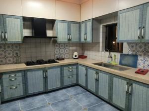 a kitchen with blue cabinets and a sink at Beach villa South Goa in Arossim-Cansaulim