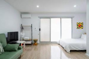 Brunswick Convenience 1BR Home في ملبورن: غرفة نوم بيضاء بسرير واريكة خضراء