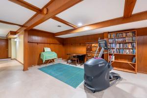 a room with a book shelf and a table with a suitcase at Spacious 4BR Home with BBQ Yard Near Golf Course in Rockford