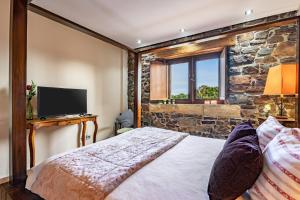 a bedroom with a bed with a stone wall at Casona Asturiana Los Gamonales in Logrezana