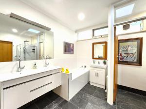 5 bedroom suite sleeps 16 with fully equipped kitchen & two bathrooms في Highett: حمام به مغسلتين ومرآة كبيرة