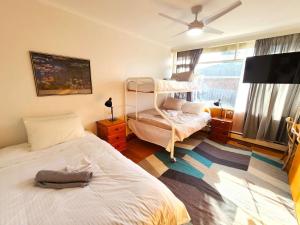 5 bedroom suite sleeps 16 with fully equipped kitchen & two bathrooms في Highett: غرفة نوم بها سريرين وتلفزيون بشاشة مسطحة +39 صورة