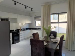 una cucina con tavolo e sedie e una cucina con tavolo e cucina di Longhorn Ibex Apartments a Lusaka