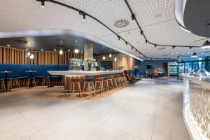 a bar in a restaurant with blue walls and stools at NH Graz City in Graz +48 photos