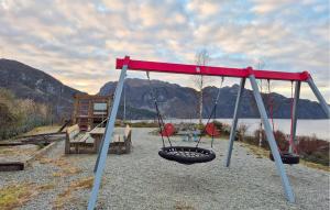 Dos columpios en un parque infantil con un lago al fondo en Amazing Apartment In Forsand With House Sea View, en Helle