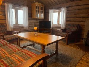 ein Wohnzimmer mit einem Holztisch und einem TV in der Unterkunft Charming Cabin with Old Timber, Fireplace & Views in Beitostøl