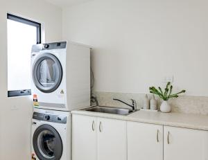 a kitchen with a washing machine and a sink at Curragudde Cove - Pambula Beach in Pambula Beach
