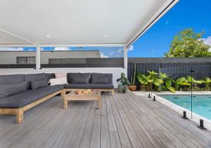 a patio with a couch and a table and a pool at Coastal Nest - Walk to Windang Beach in Windang