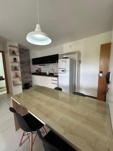 a kitchen with a table with chairs and a refrigerator at Flat Resort ILOA in Barra de São Miguel +8 photos