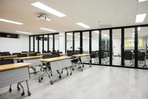 a classroom with tables and chairs and windows at 여주여행자센터 호스텔 in Yeoju