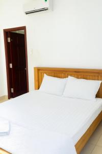 ein Schlafzimmer mit einem Bett mit weißer Bettwäsche und einer Tür in der Unterkunft Hạ Vy Hotel Hồ Chí Minh in Ho-Chi-Minh-Stadt