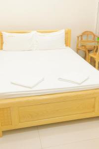 - un lit en bois dans une chambre avec 2 chaises dans l'établissement Hạ Vy Hotel Hồ Chí Minh, à Hô-Chi-Minh-Ville