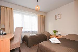 a hotel room with two beds and a desk and a window at Hotel Dom Polonii in Ostróda +36 photos