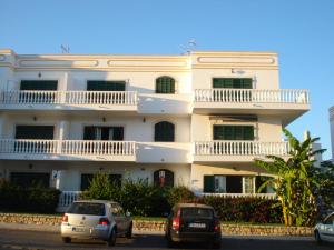 a white building with cars parked in front of it at Apartment Moni Cabanas de Tavira Algarve in Cabanas de Tavira