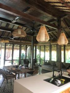 een woonkamer met tafels en stoelen en hanglampen bij Heliconia Joglo House in Sempidi