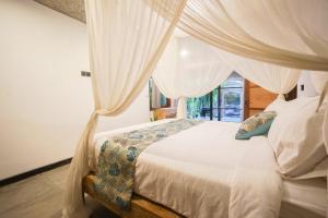 een slaapkamer met een hemelbed bij Heliconia Joglo House in Sempidi