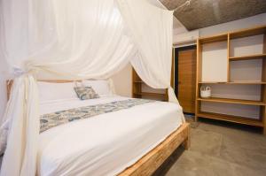 een slaapkamer met een wit bed met een hemelbed bij Heliconia Joglo House in Sempidi +2 foto's