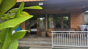 een veranda van een huis met glazen deuren bij Heliconia Joglo House in Sempidi