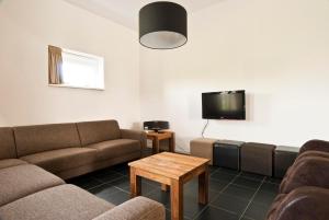 een woonkamer met twee banken en een tv bij Group Accommodation for up to 48-persons in Wemeldinge +20 foto's