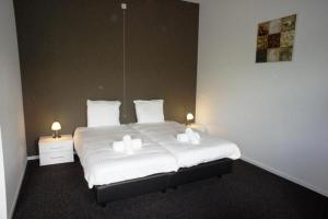 een slaapkamer met een groot wit bed met twee lampen bij Group Accommodation for up to 48-persons in Wemeldinge