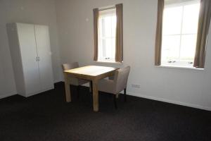 een kamer met een houten tafel en stoelen en twee ramen bij Group Accommodation for up to 48-persons in Wemeldinge
