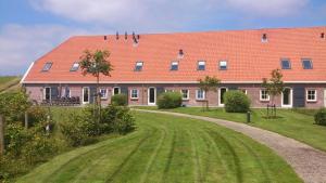 een groot gebouw met een rood dak en een onverharde weg bij Group Accommodation for up to 48-persons in Wemeldinge