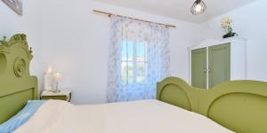 a bedroom with a green bed and a window at Pino 1 in Veli Lošinj