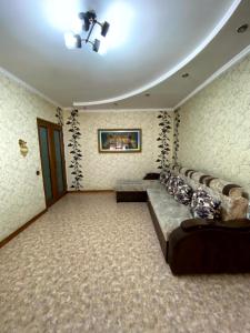 ein Wohnzimmer mit einem Sofa in einem Zimmer mit Tapete in der Unterkunft Иляева 40 парк Кен Баба in Schymkent + 9 Fotos