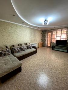 ein großes Wohnzimmer mit Sofas und einem TV in der Unterkunft Иляева 40 парк Кен Баба in Schymkent