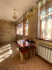 ein Esszimmer mit einem Tisch und einigen Fenstern in der Unterkunft Иляева 40 парк Кен Баба in Schymkent