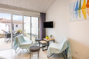 un soggiorno con sedie bianche e un balcone di Agréable Maison Sablaise a Les Sables-dʼOlonne