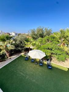 an umbrella and chairs on a green lawn at Aurora Gardens Villa Spacious 3 Bedroom in Protaras in Paralimni