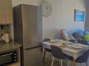 a kitchen with a table with chairs and a clock on the wall at Arena Sol by HelloApartments in Puerto de Santiago