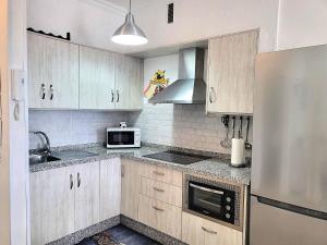 a kitchen with wooden cabinets and a stainless steel refrigerator at Arena Sol by HelloApartments in Puerto de Santiago +22 photos