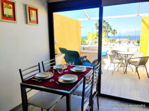 Una mesa de comedor y sillas con vista a un patio. en Ocean View Playa la Arena by HelloApartments, en Puerto de Santiago