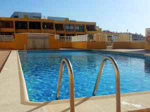 Una piscina con agua azul frente a un edificio. en Ocean View Playa la Arena by HelloApartments, en Puerto de Santiago