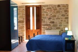 Un dormitorio con una cama azul y una pared de piedra en Il Vicolo, en Tortorici