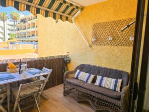 a patio with a couch and a table on a balcony at Arena Beach by HelloApartments in Puerto de Santiago