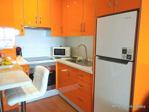 a kitchen with orange cabinets and a white refrigerator at Sea View Playa Arena by HelloApartments in Puerto de Santiago